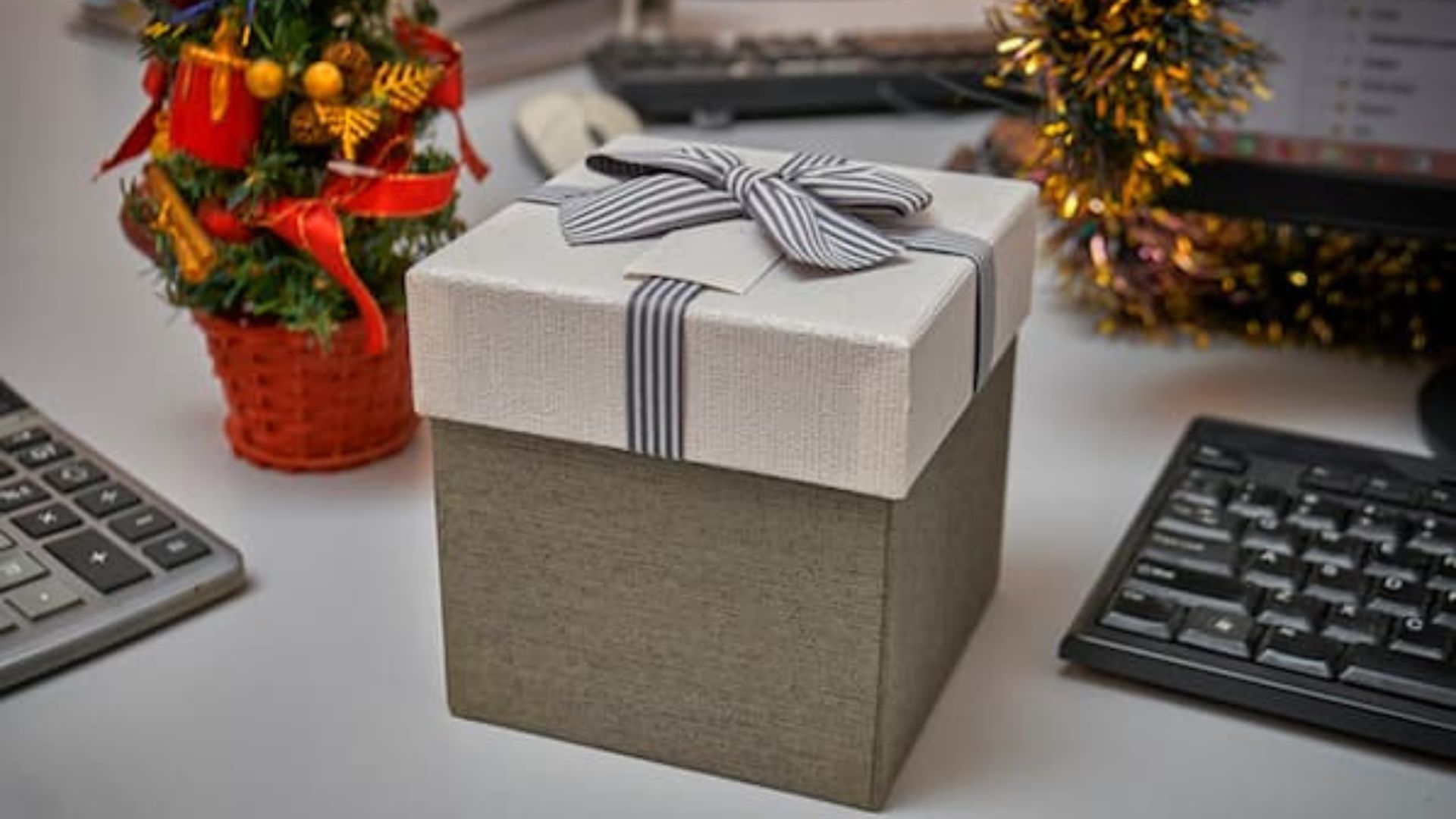 Secret Santa Gift in a grey box and laptops and flowers in the background